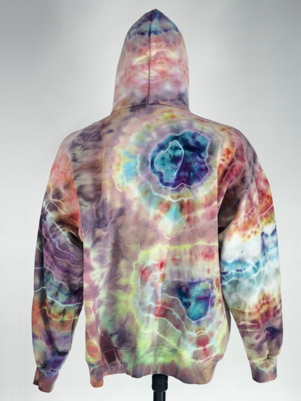 Back View of extra-large heavyweight hoodie. "Kinetic Implosion" captures the moment of catastrophic energy collapsing inward. Through a rigorous 24-hour ice-melt process, we have harnessed the slow transition of melting ice to fracture pigments into intricate, high-velocity patterns. The resulting crystalline "shards" of color create a sense of movement and raw power that is unique to this specific artifact.