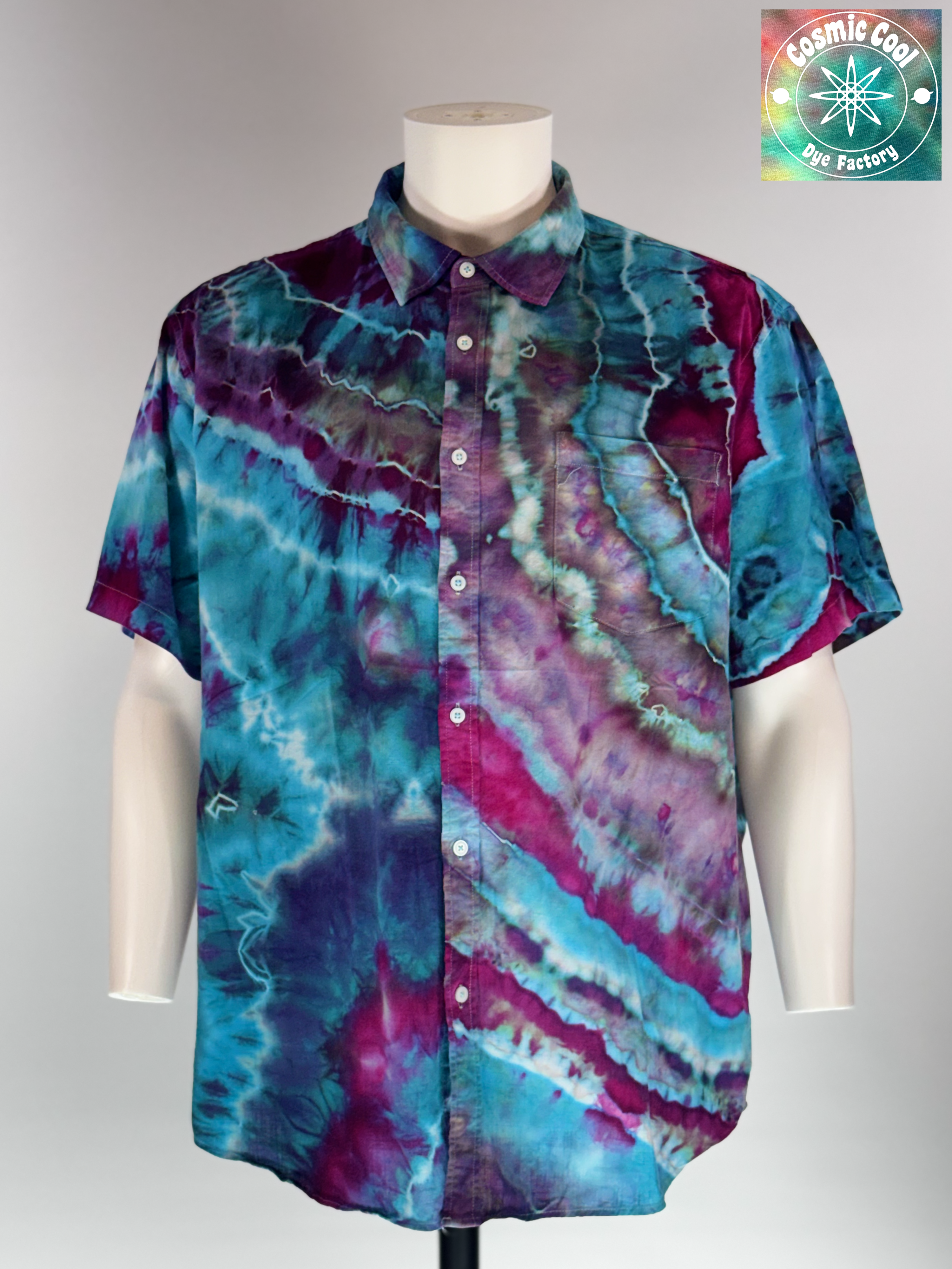 Front view of our Cosmic Camp Shirt. Geodesic tides mimics the rhythmic, mineral-like layering found in coastal geodes. The design features a cascading flow of deep amethyst and royal purple waves that wash over a vibrant turquoise and teal base.