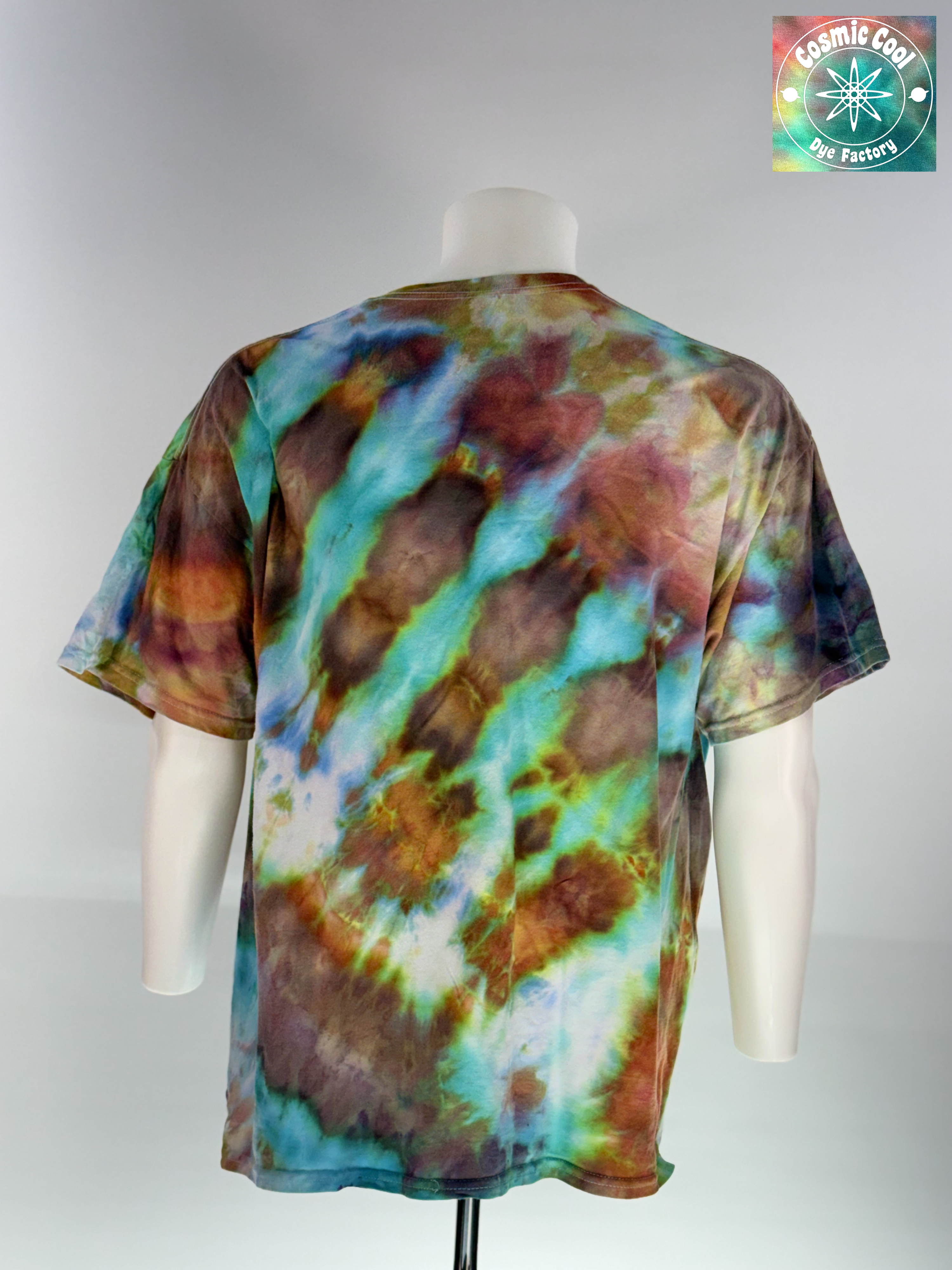 Back view of a 2XL Short Sleeve Artisan Tee. Phoenix Elixir features a high-energy, diagonal flow of color. The design is dominated by radiant teals and ethereal sky blues that are "invaded" by scorched earth umbers and molten copper highlights. These colors meld to create a shimmering, liquid effect