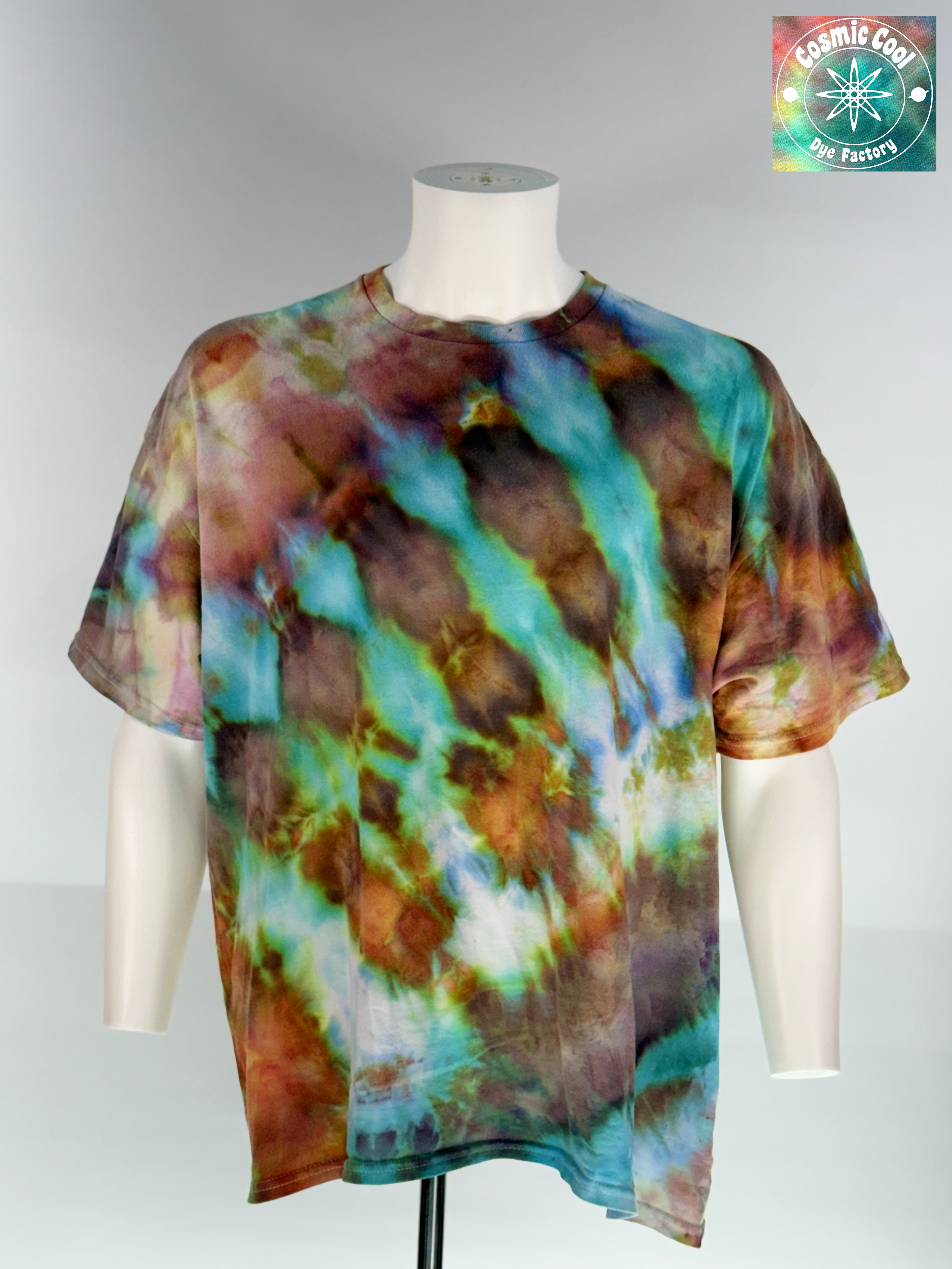 Front view of a 2XL Short Sleeve Artisan Tee. Phoenix Elixir features a high-energy, diagonal flow of color. The design is dominated by radiant teals and ethereal sky blues that are "invaded" by scorched earth umbers and molten copper highlights. These colors meld to create a shimmering, liquid effect