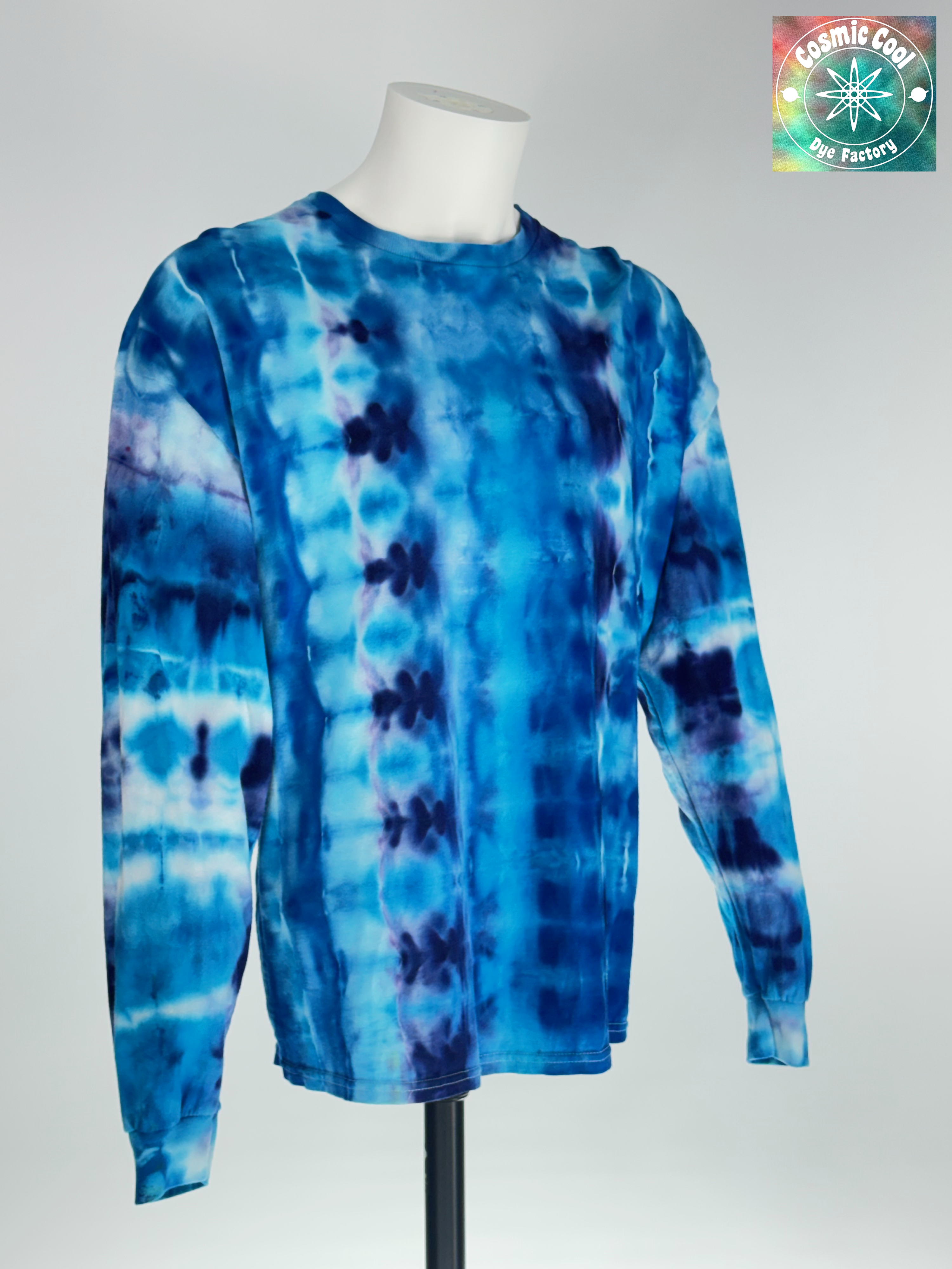Angled 3/4 Front view 2XL Long Sleeve Artisan Ice Dye Tee. Glacial Voyagers captures the sweeping scale of an arctic landscape. The design features horizontal "drifts" of icy turquoise and deep cerulean, broken by jagged, crystalline lines of white and soft lavender. The ice-dye creating a continuous "voyage" of color that feels vast in its detail.