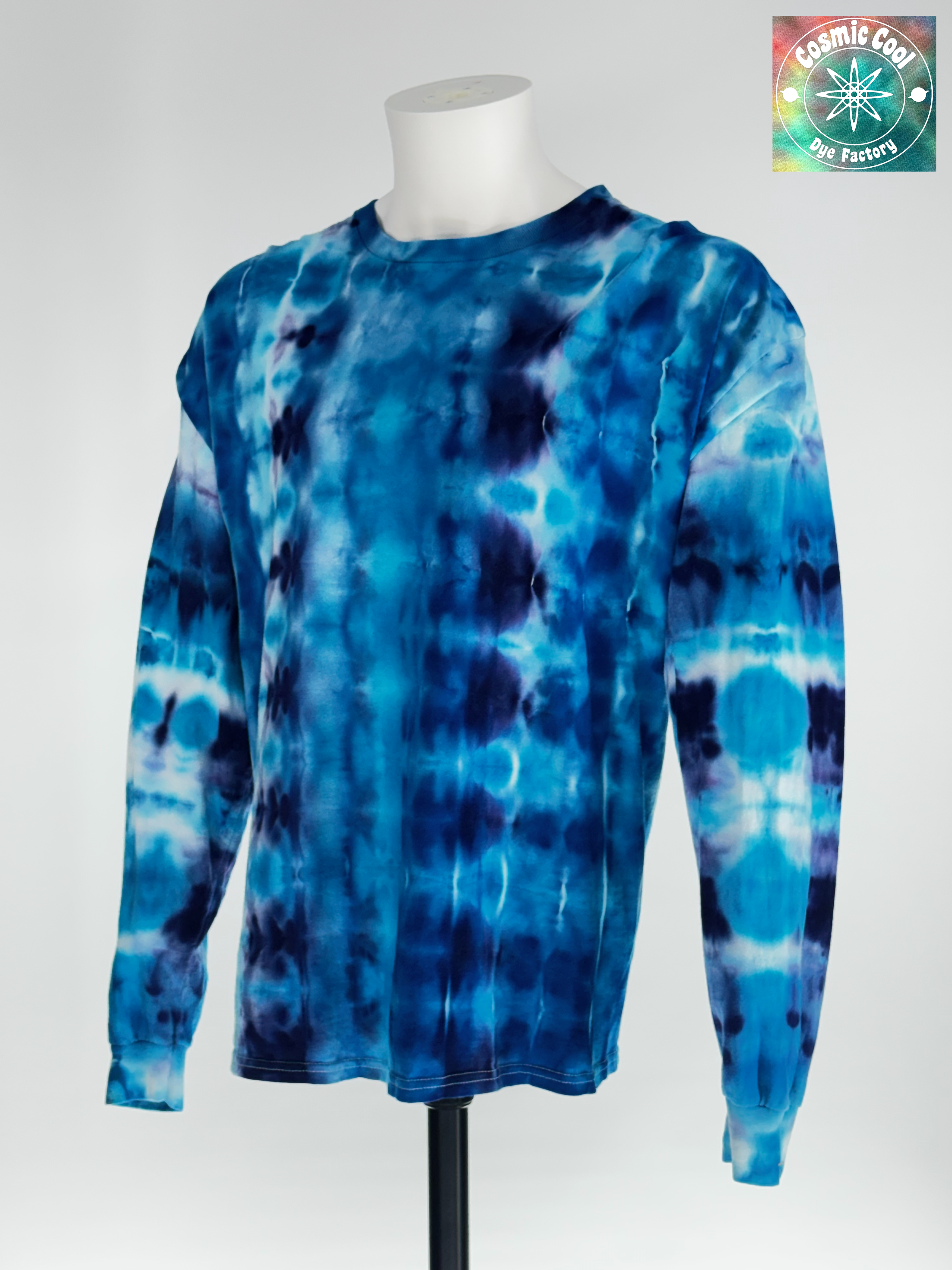 Angled 3/4 Front view of 2XL Long Sleeve Artisan Tee. Glacial Voyagers" captures the sweeping scale of an arctic landscape. The design features horizontal "drifts" of icy turquoise and deep cerulean, broken by jagged, crystalline lines of white and soft lavender. The ice-dye creating a continuous "voyage" of color that feels vast in its detail.