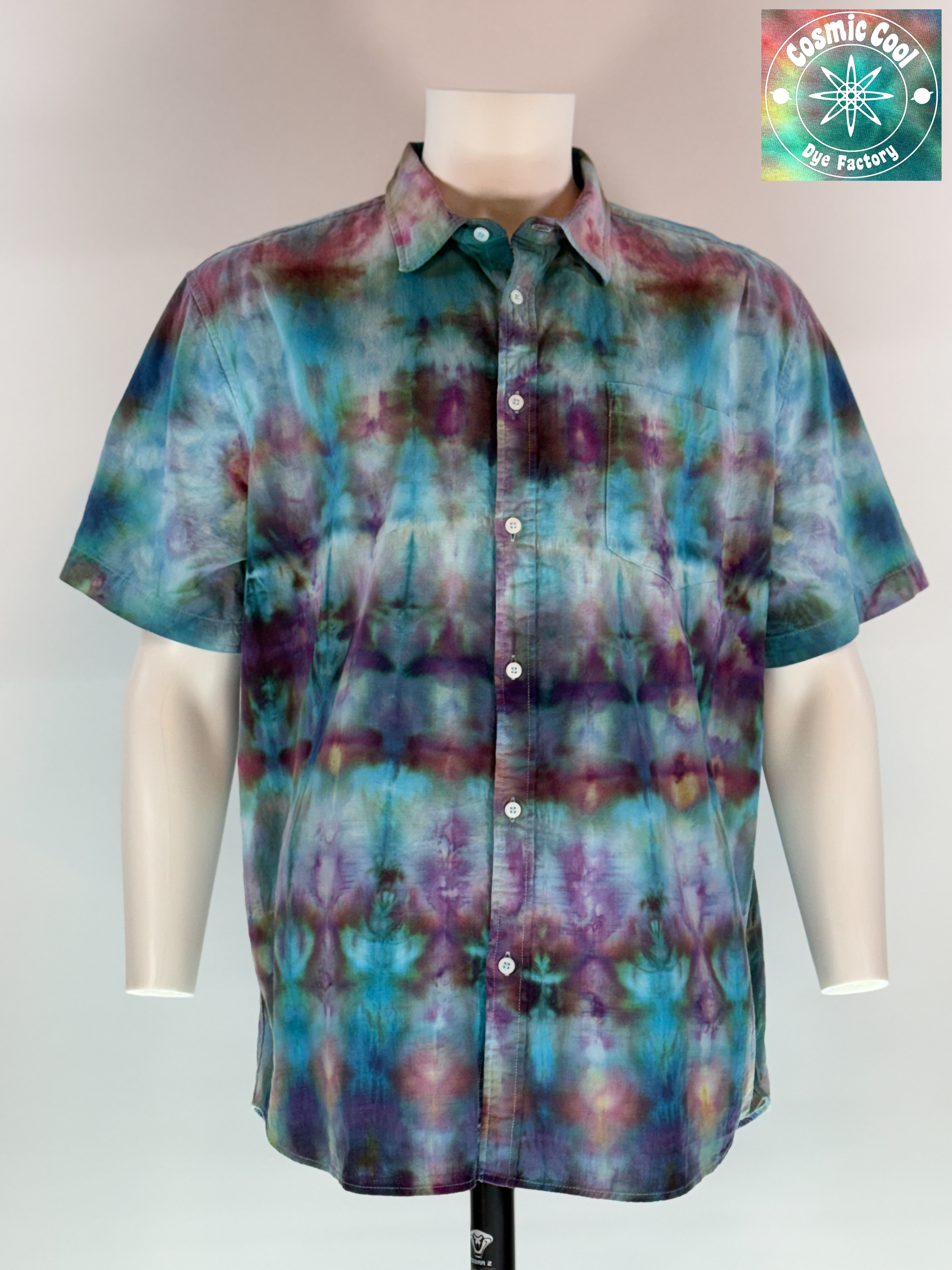 A vertical video of  the extra-large Men's Ice Dye Cam Shirt. Our Nebula Drift short sleeve button down, collared shirt features a design saturated with amethysts and turquoise. Ice flow creating the watercolor like transitions across the fabric.